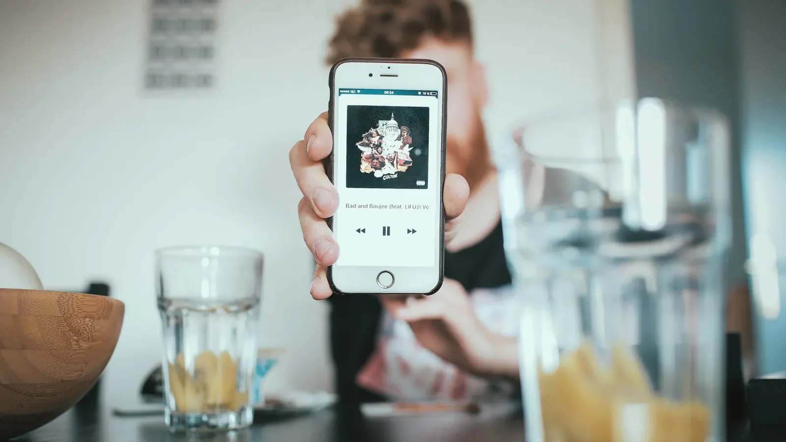Person holding a smartphone displaying a media player app