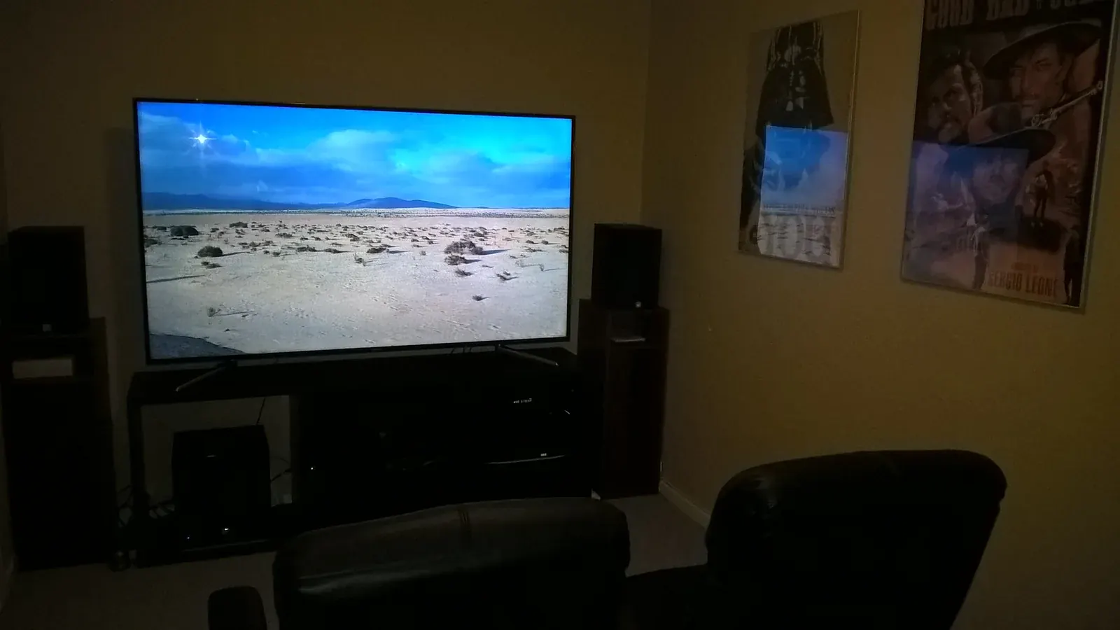 Large television playing a film in a home theater room with movie posters on the wall